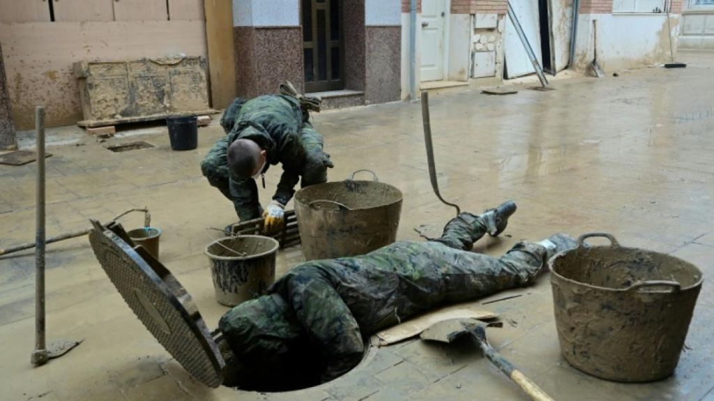 Des soldats évacuent la boue d'un égout à Paiporta, au sud de Valence, dans l'est de l'Espagne, le 13 novembre 2024, à la suite d'inondations meurtrières